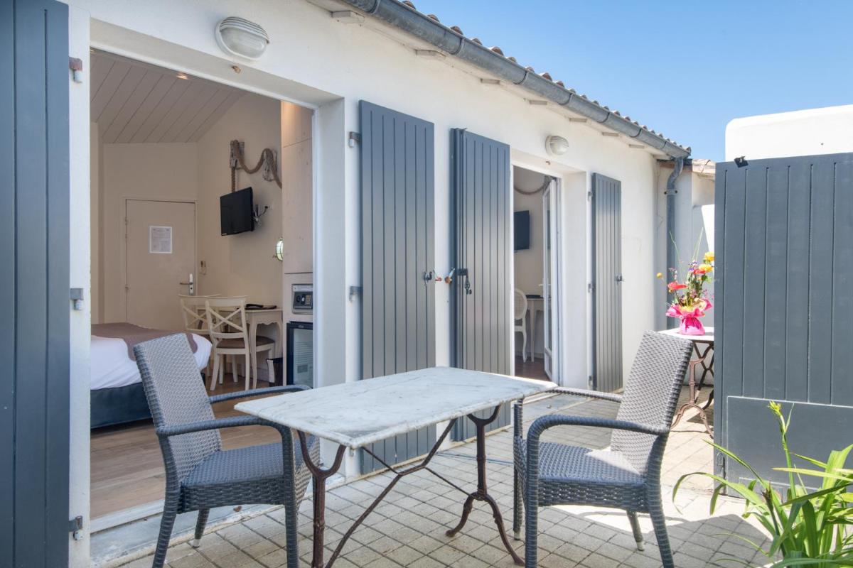 un patio avec une table et des chaises sur un balcon dans l'établissement Hôtel Restaurant & Spa Plaisir, au Bois-Plage-en-Ré