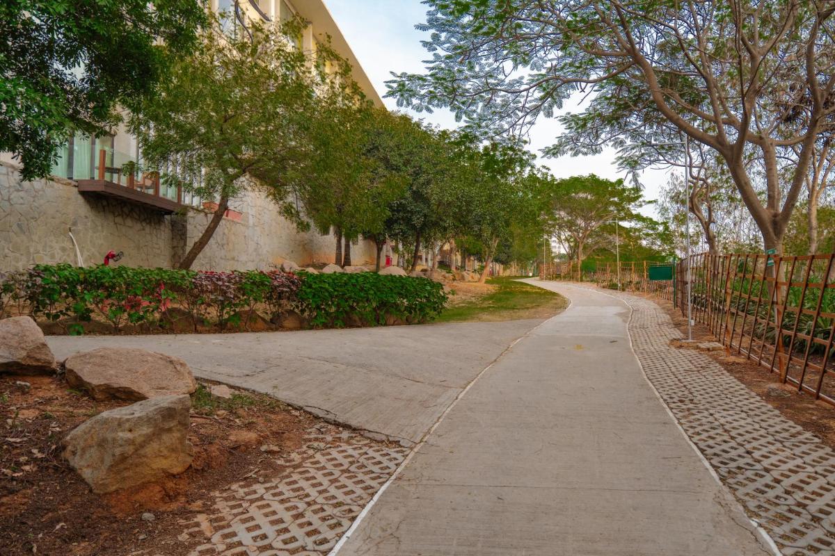 an empty sidewalk in front of a building with trees at Hyatt Hyderabad Gachibowli in Hyderabad