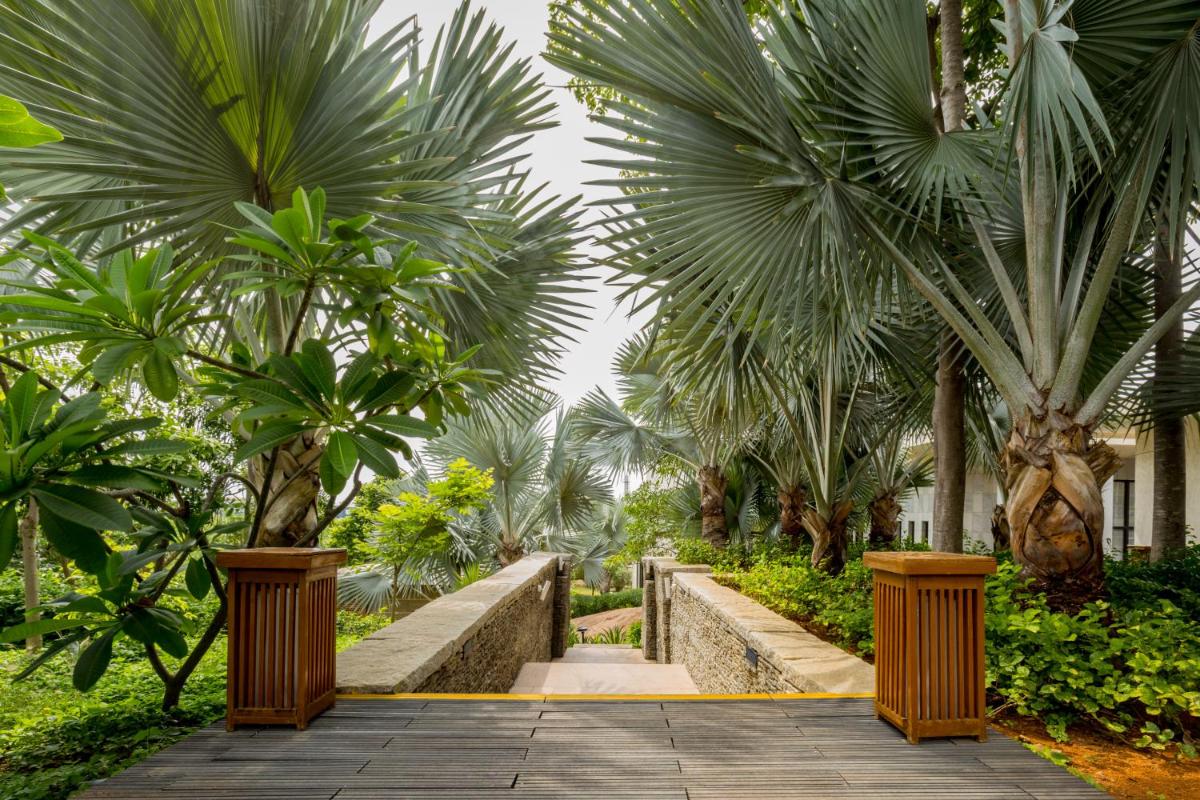 a walkway through a garden with palm trees at Hyatt Hyderabad Gachibowli in Hyderabad