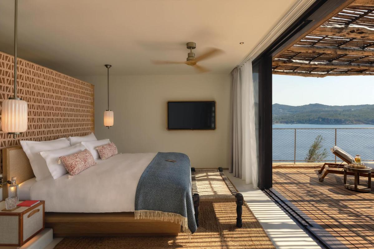 Un dormitorio con una cama y un balcón con televisión. en Six Senses Ibiza, en Portinatx