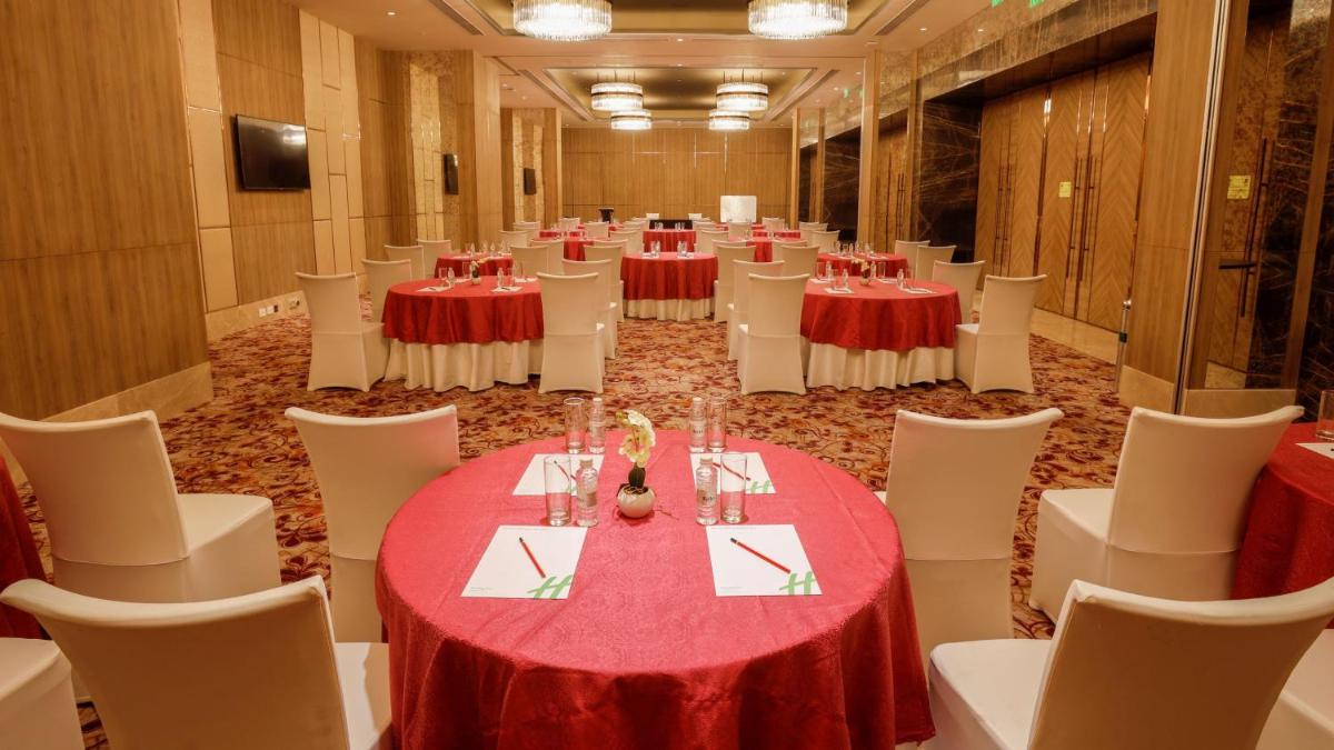 a large room with tables and white chairs at Holiday Inn Gurugram Sector 90 by IHG in Gurgaon