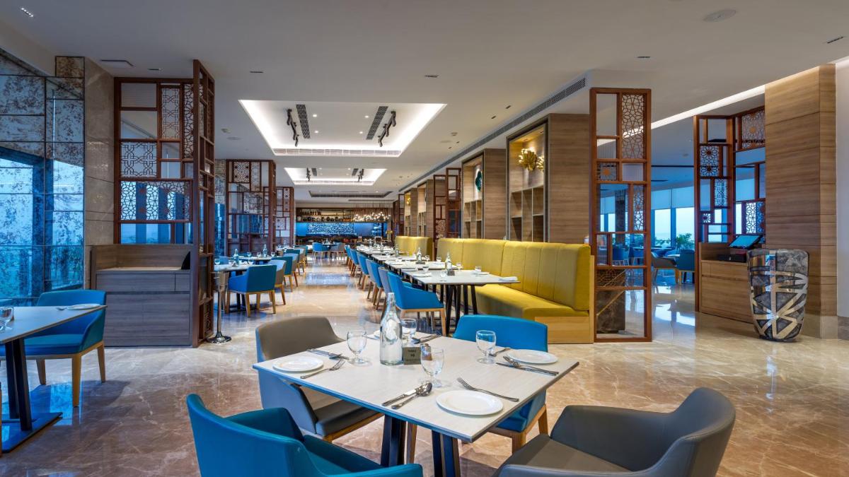 a restaurant with white tables and blue chairs at Holiday Inn Gurugram Sector 90 by IHG in Gurgaon a restaurant with white tables and blue chairs at Holiday Inn Gurugram Sector 90 by IHG in Gurgaon
