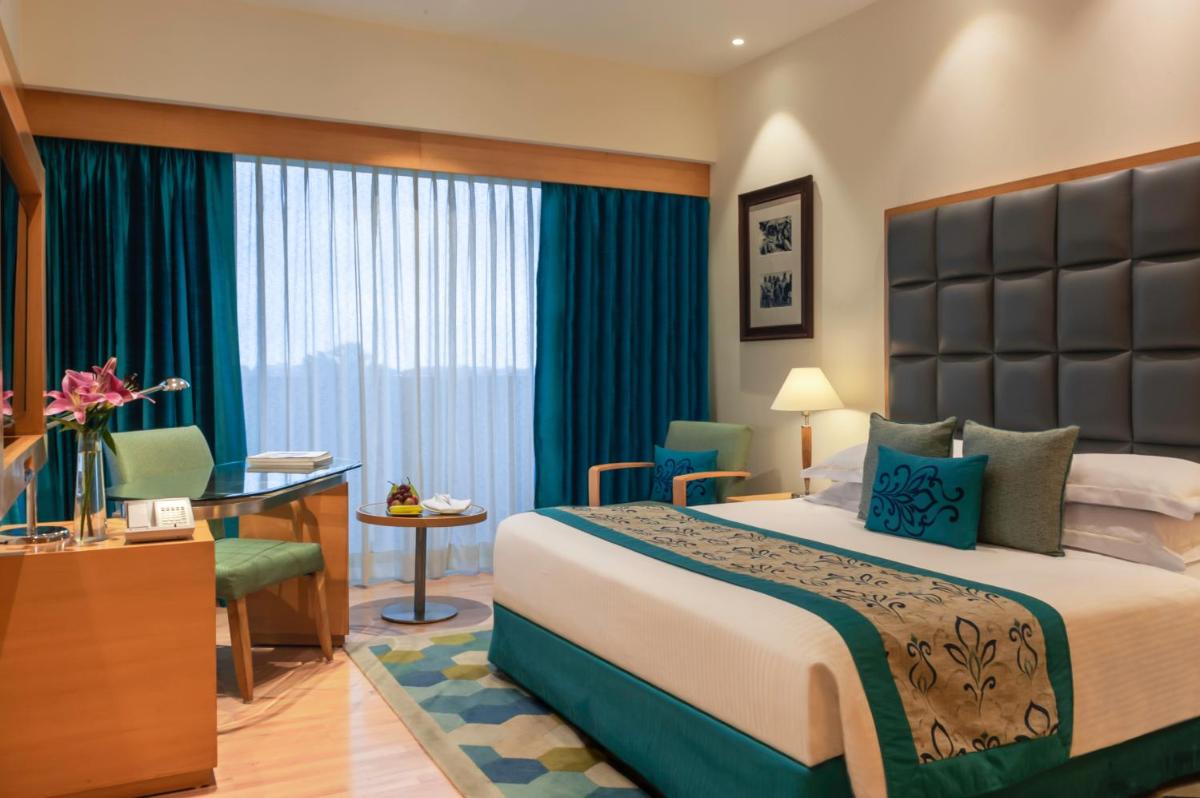 a hotel room with a large bed and a desk at Taj Chandigarh in Chandīgarh