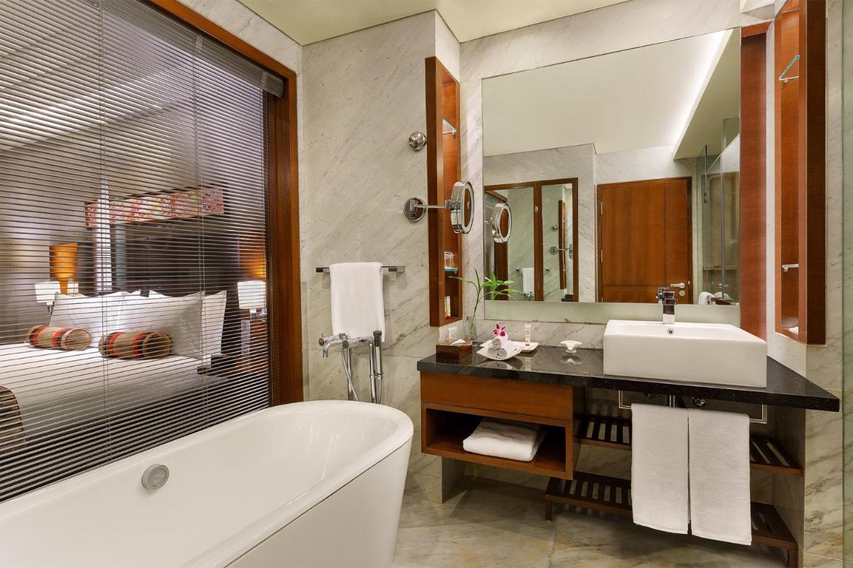 a bathroom with a tub and a sink and a mirror at Crowne Plaza Today Gurugram by IHG in Gurgaon