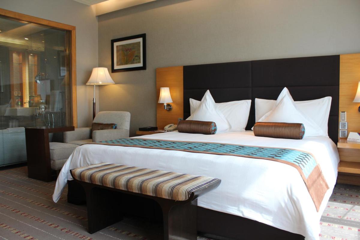 a hotel room with a large bed and a chair at Crowne Plaza Today Gurugram by IHG in Gurgaon