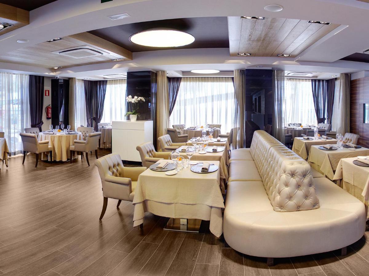 un comedor con mesas y sillas blancas y registradora en Cosmopolita Hotel Boutique & Spa, en Platja d'Aro