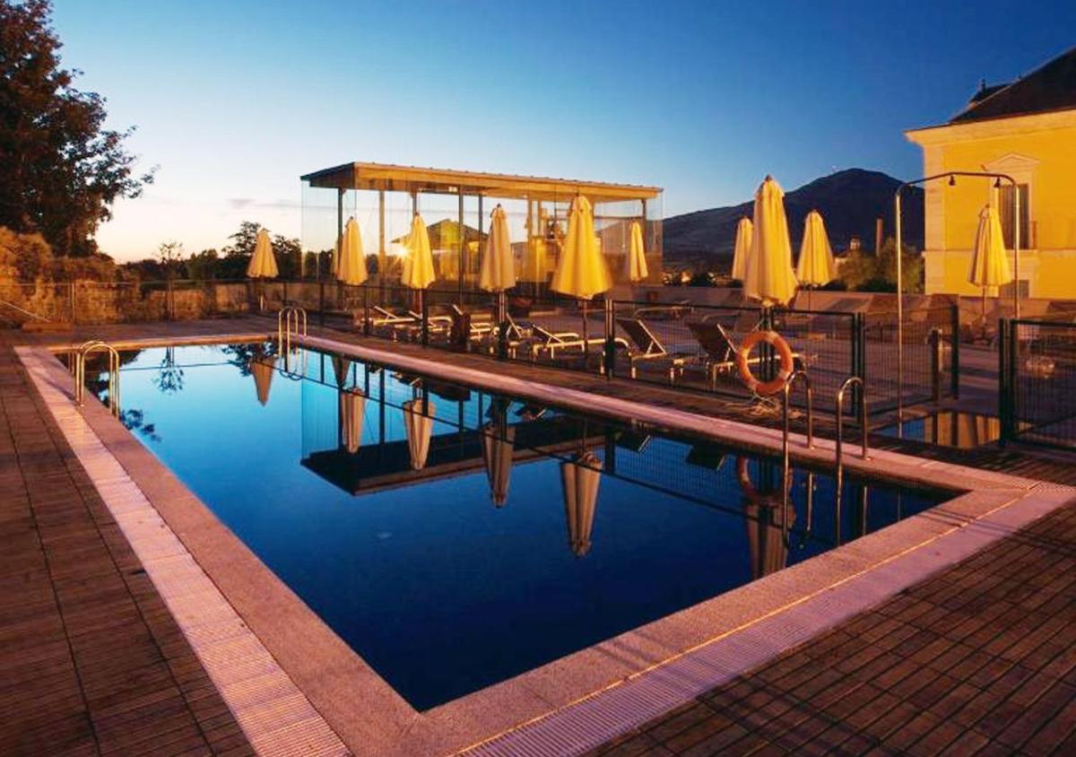 Una piscina con sillas y sombrillas al lado en Parador de La Granja, en La Granja de San Ildefonso