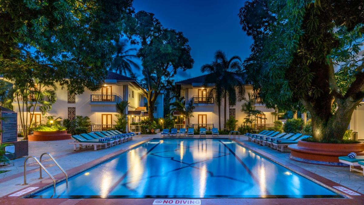 a swimming pool in front of a hotel at night at Radisson Goa Candolim in Candolim