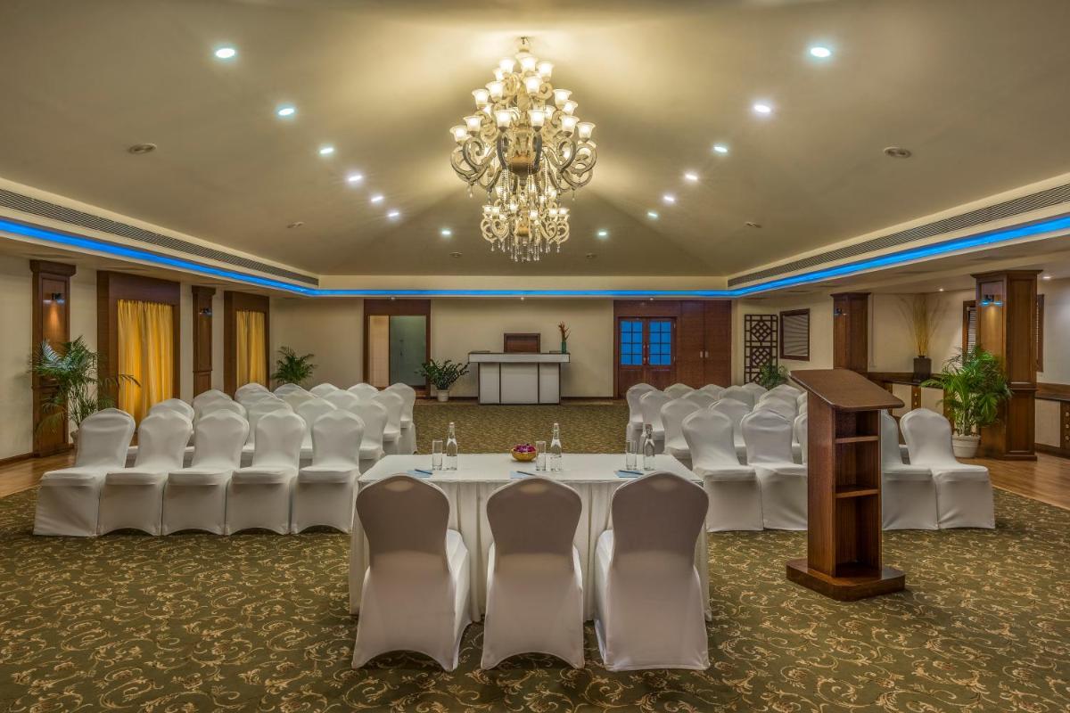 a conference room with white chairs and a table and a chandelier at Radisson Goa Candolim in Candolim
