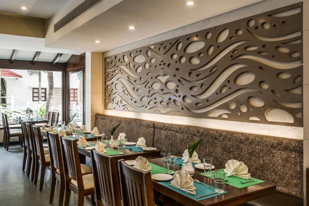 a restaurant with tables and chairs and a wall with a mural at Radisson Goa Candolim in Candolim