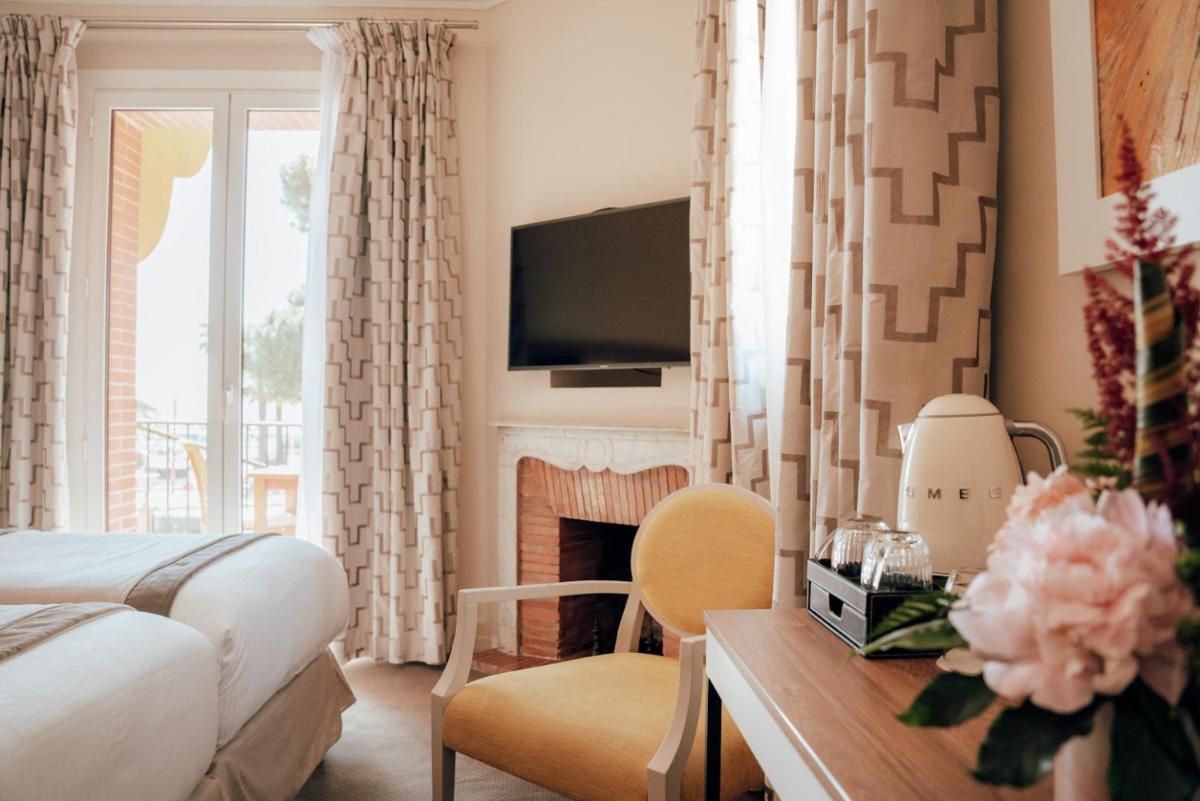 - une chambre avec un lit, une cheminée et une télévision dans l'établissement Ermitage de l'Oasis & Spa - Cannes Mandelieu, à Mandelieu-la-Napoule