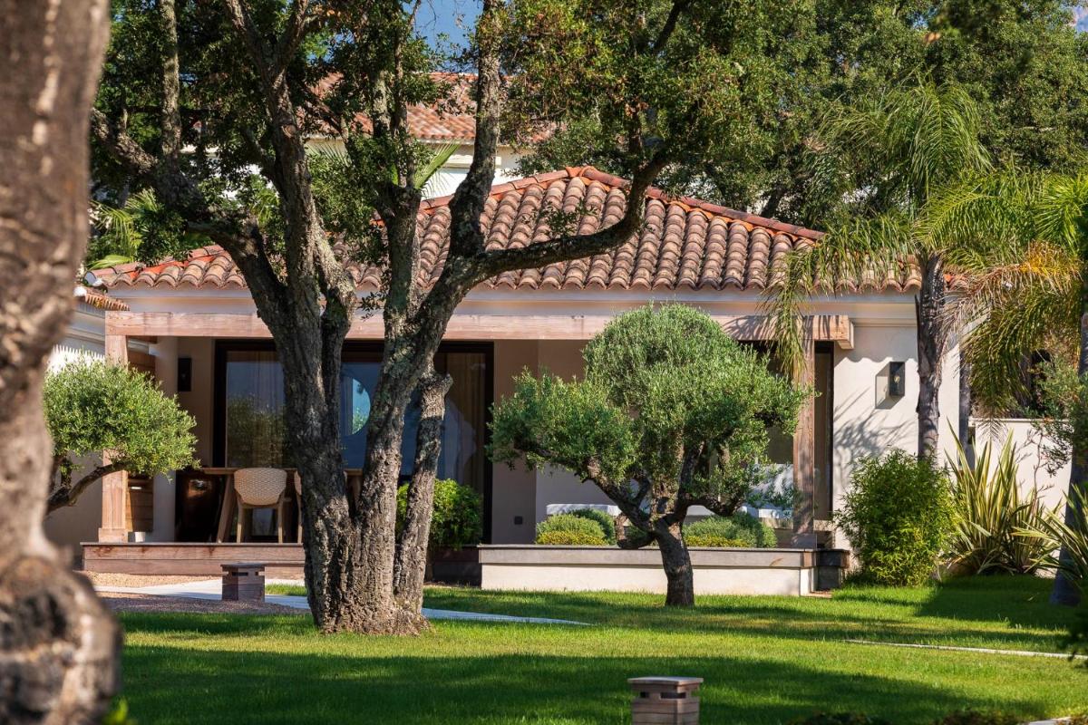 une maison avec une cour arborée devant elle dans l'établissement Hotel Don Cesar, à Porto-Vecchio