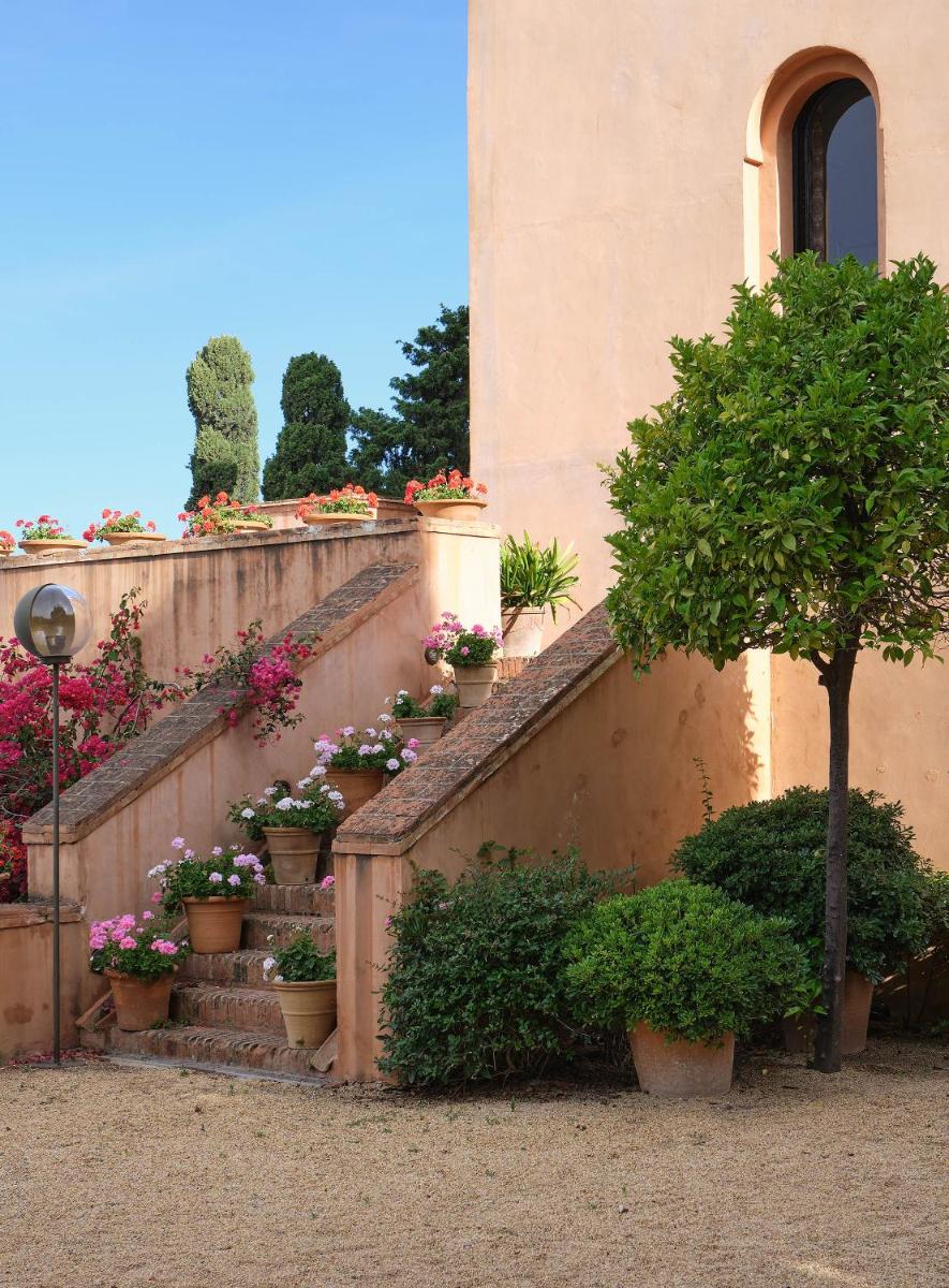 Un edificio con una escalera con plantas en macetas y un árbol. en Soho Boutique Castillo de Santa Catalina - Adults Recommended, en Málaga
