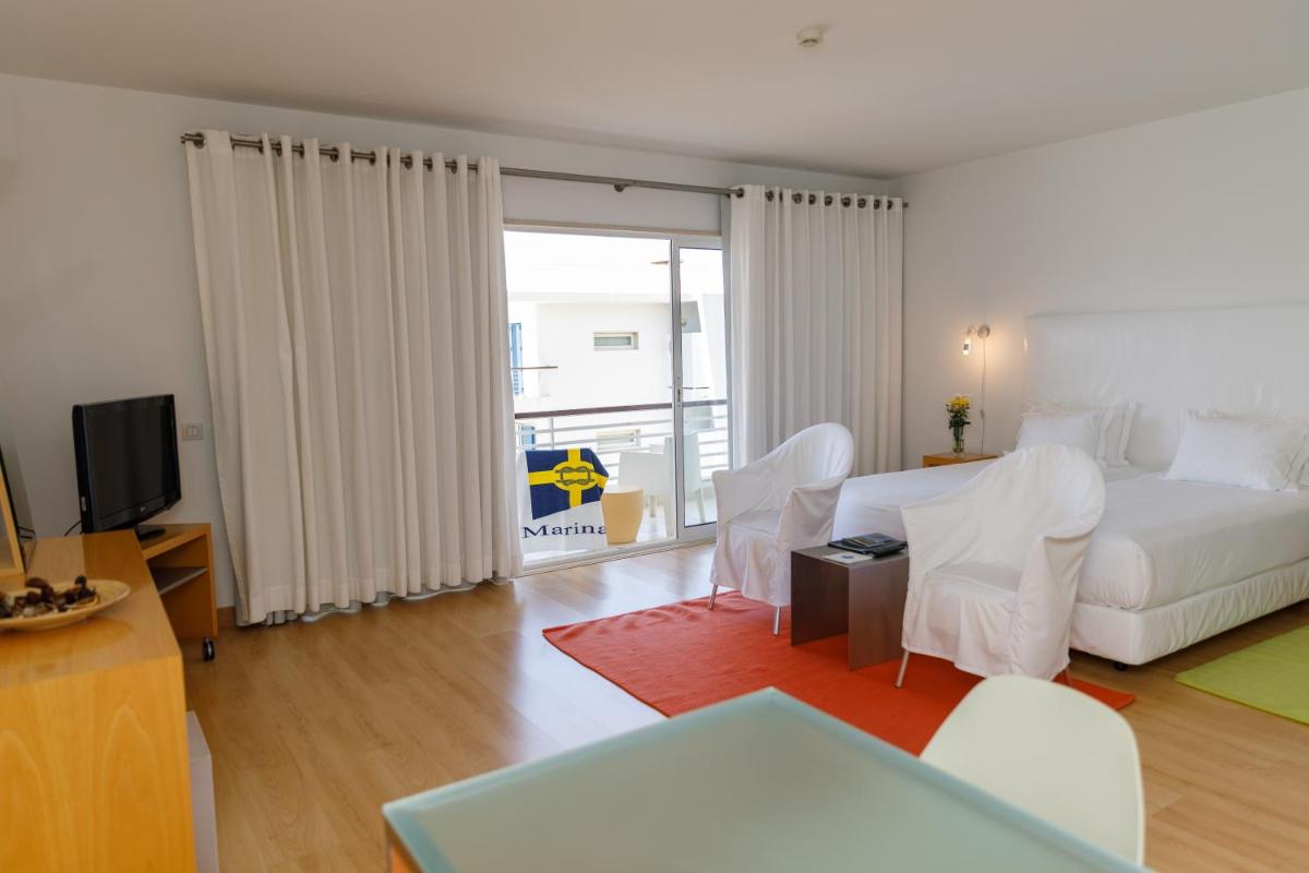 uma sala de estar com uma cama branca e uma televisão em Marina Club Lagos Resort em Lagos