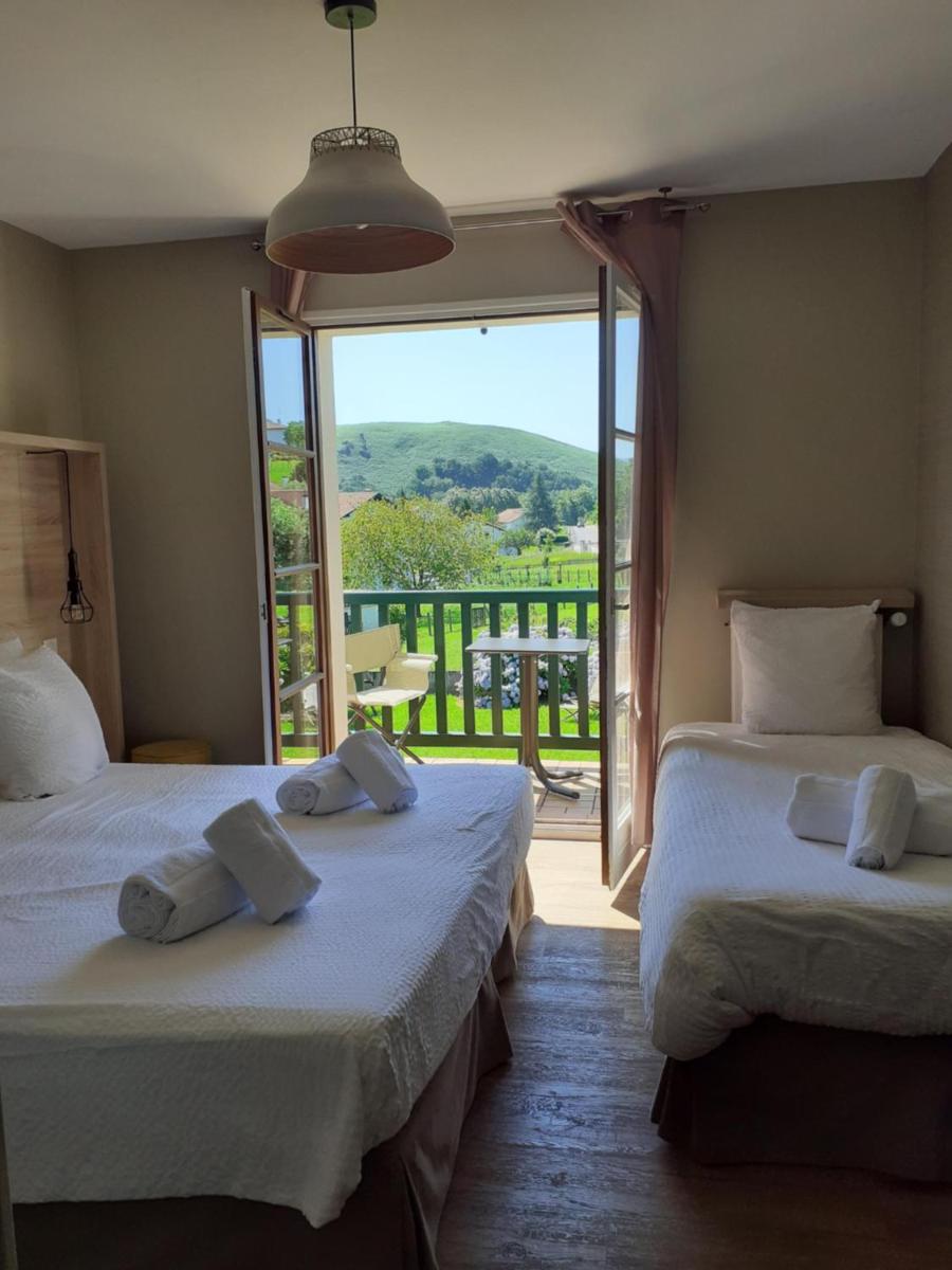 deux lits dans une chambre avec une grande fenêtre dans l'établissement Hotel Mendionde, à Saint-Pée-sur-Nivelle