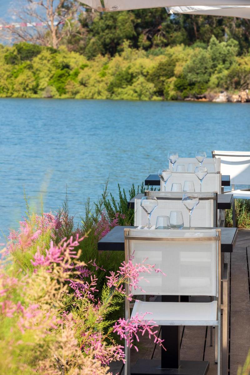 une rangée de tables et de chaises sur un quai à côté d'un lac dans l'établissement Hotel Don Cesar, à Porto-Vecchio