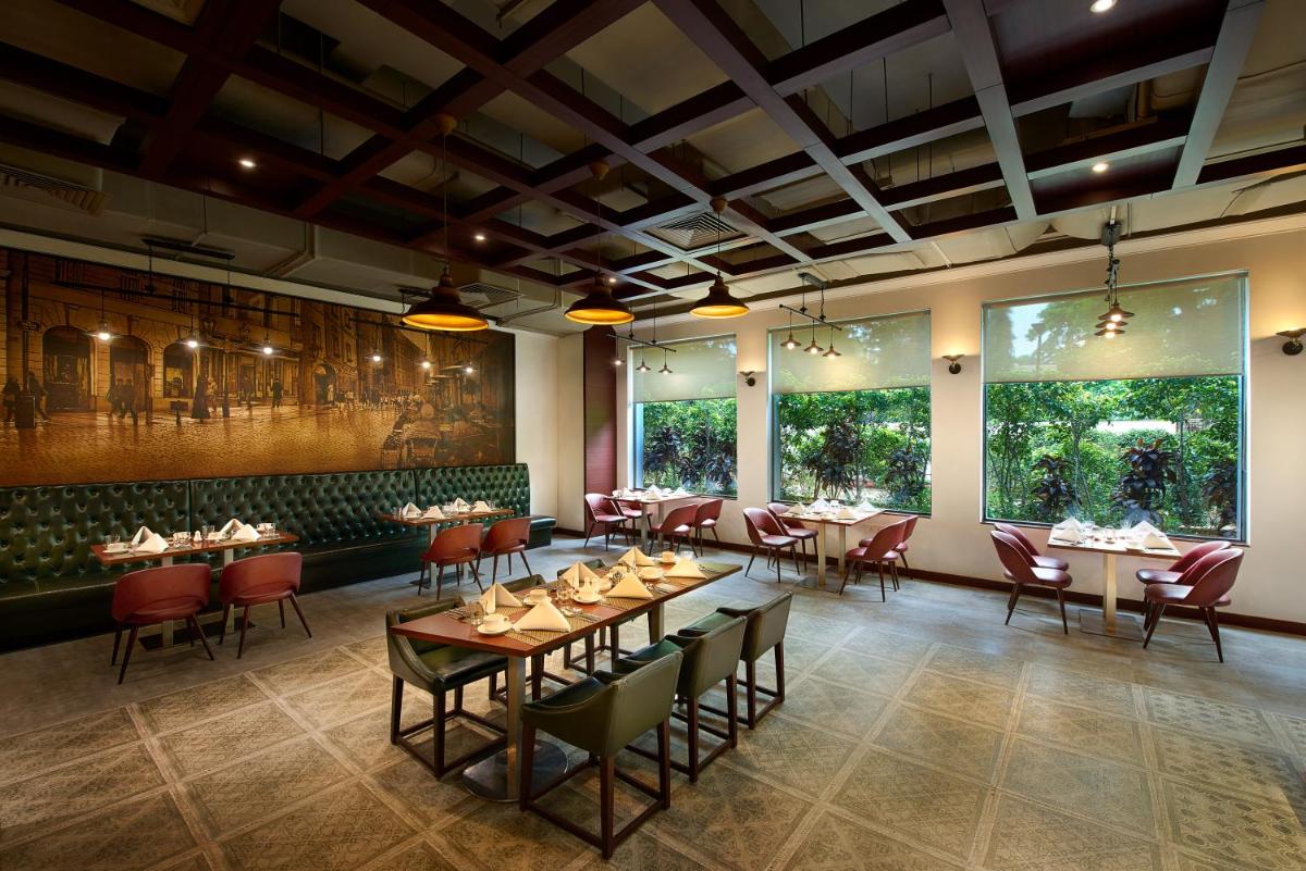 a dining room with tables and chairs and large windows at The Accord Metropolitan in Chennai