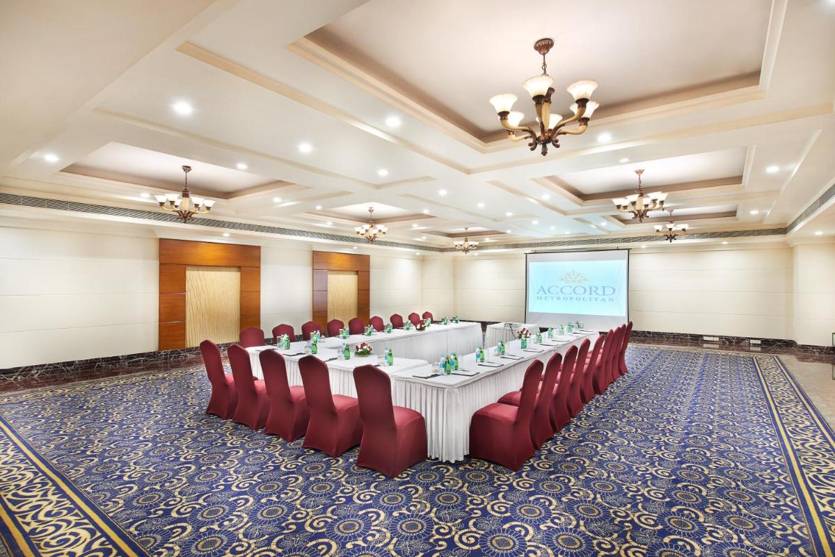 a meeting room with a long table and red chairs at The Accord Metropolitan in Chennai
