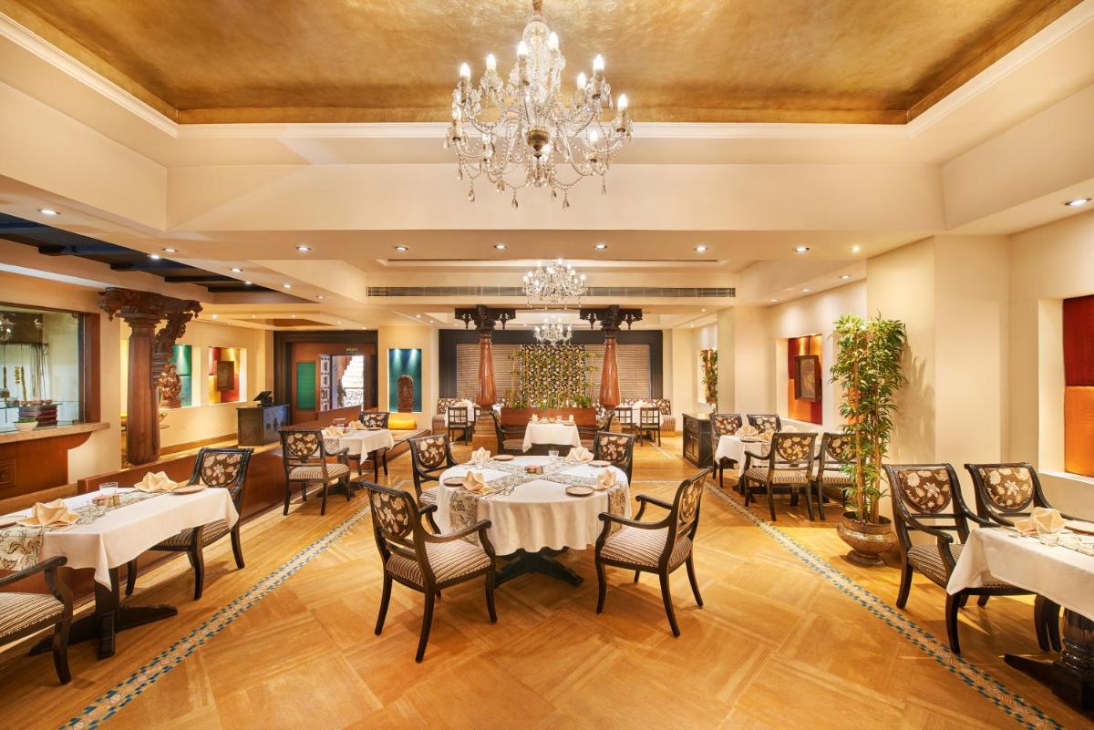 a dining room with tables and chairs and a chandelier at The Accord Metropolitan in Chennai