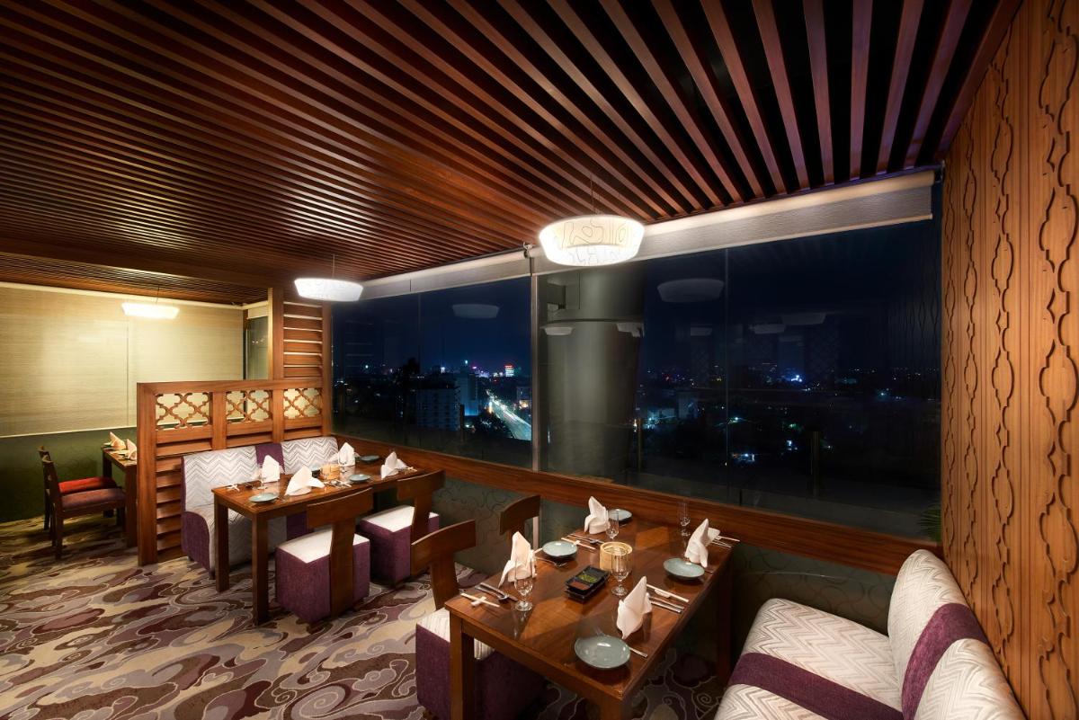 a restaurant with tables and chairs and a large window at The Accord Metropolitan in Chennai