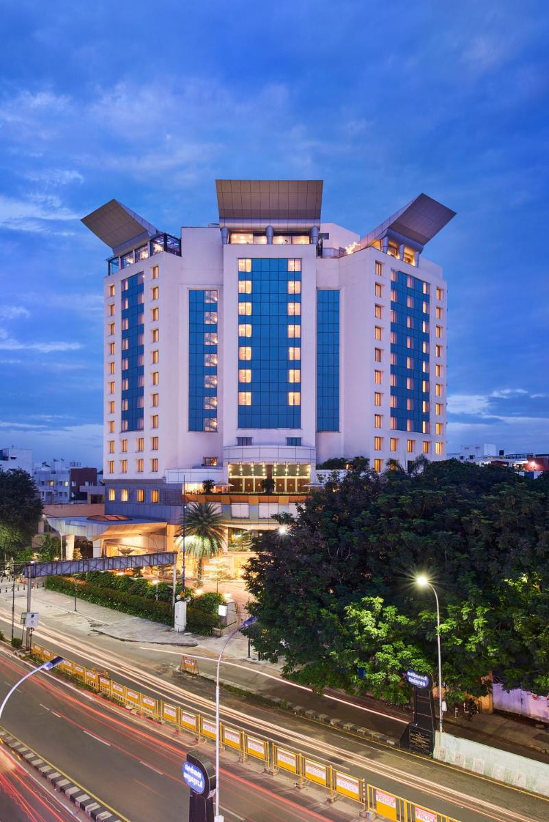a large white building with blue windows next to a street at The Accord Metropolitan in Chennai