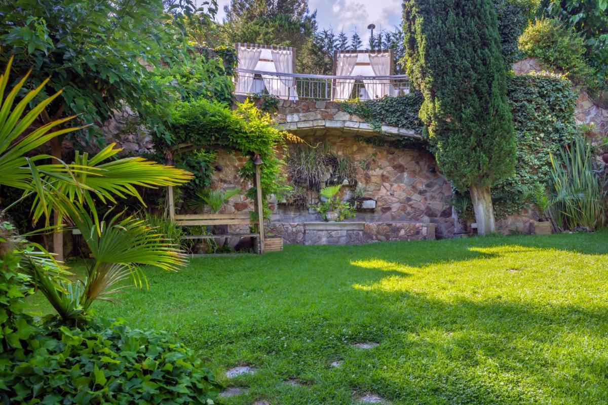 Un jardín con un muro de piedra y un puente. en Hotel GHT Neptuno-Tossa & Venus SPA, en Tossa de Mar