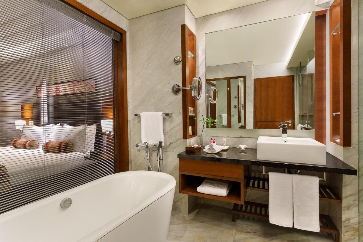 a bathroom with a tub and a sink and a mirror at Crowne Plaza Today Gurugram by IHG in Gurgaon