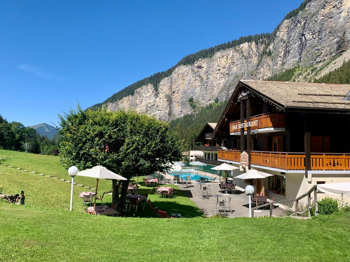 un bâtiment avec une piscine en face d'une montagne dans l'établissement Hameau des Prodains - Hôtel, à Morzine