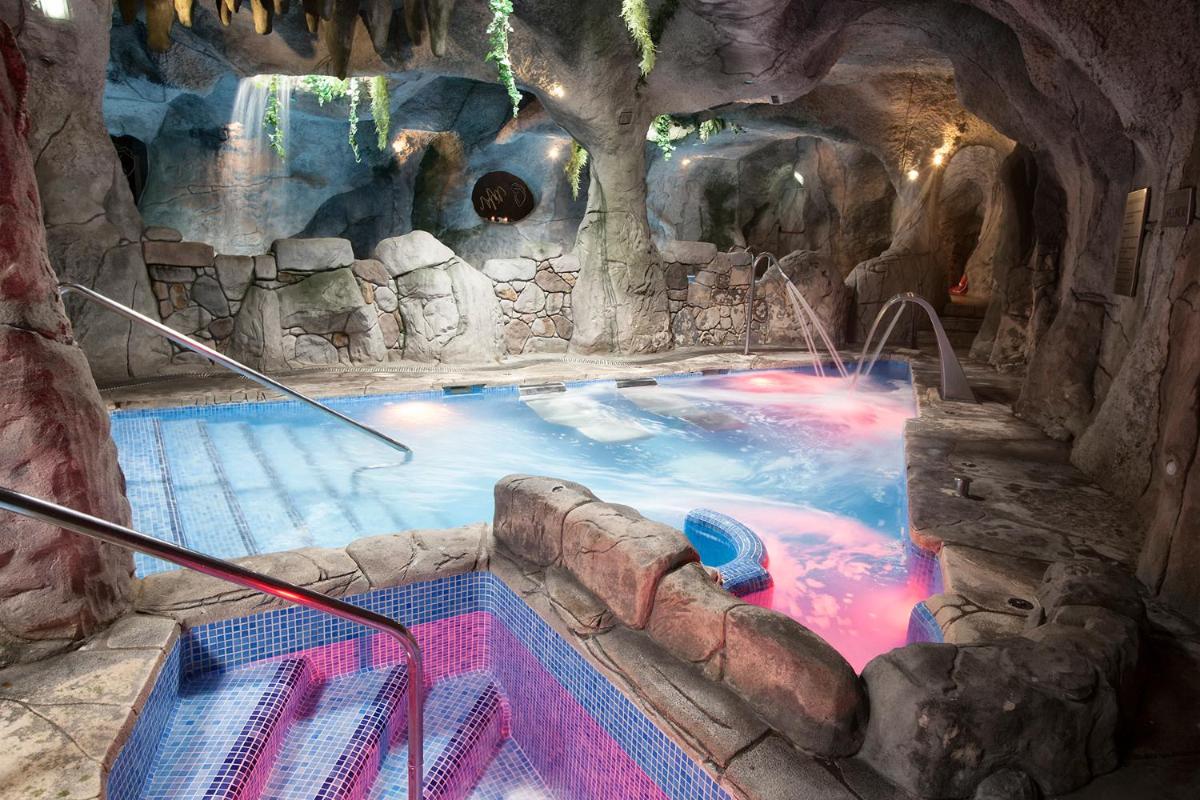 Una gran piscina en una cueva con cascada. en Hotel & Spa María Manuela, en Onís