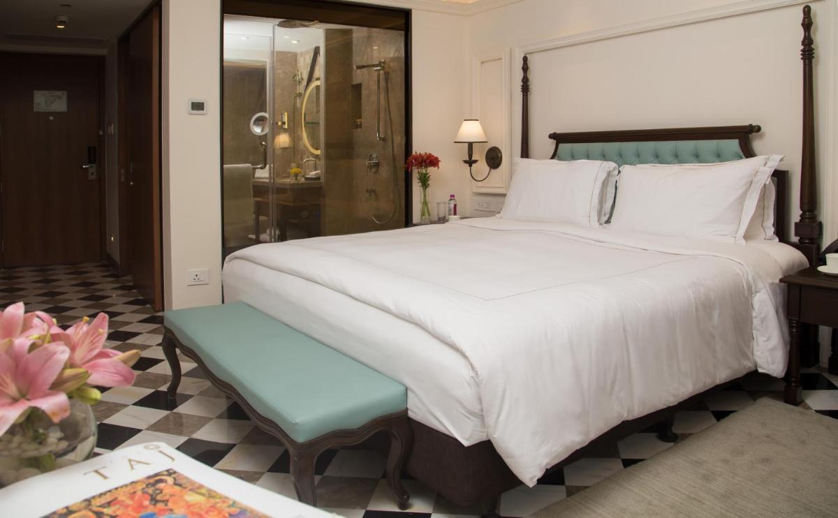 a bedroom with a large white bed and a bathroom at Taj Bengal in Kolkata