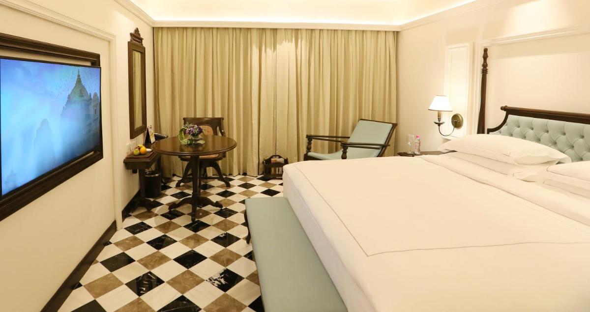a hotel room with a large bed and a tv at Taj Bengal in Kolkata