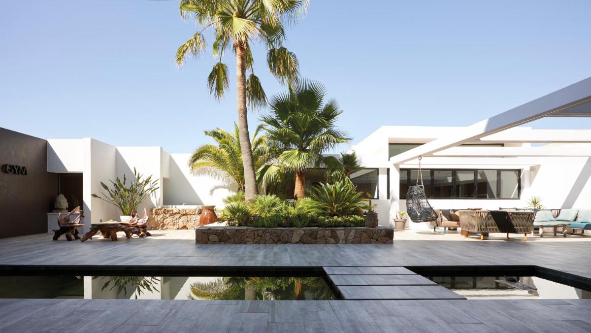 una casa con un patio con palmeras en Ibiza Corso Hotel & Spa, en Ibiza