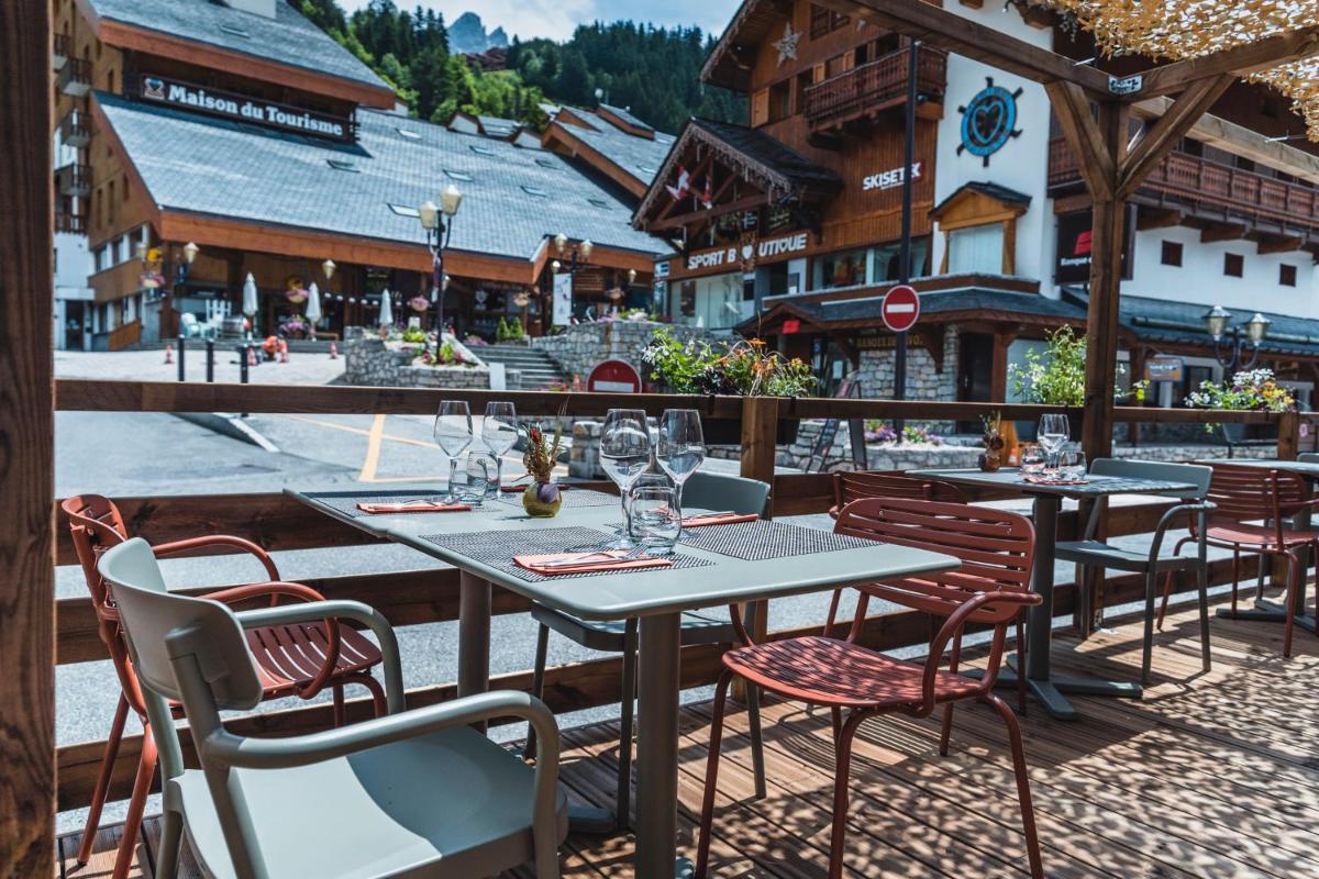 un groupe de tables et de chaises sur une terrasse dans l'établissement Hotel Le Savoy, à Méribel