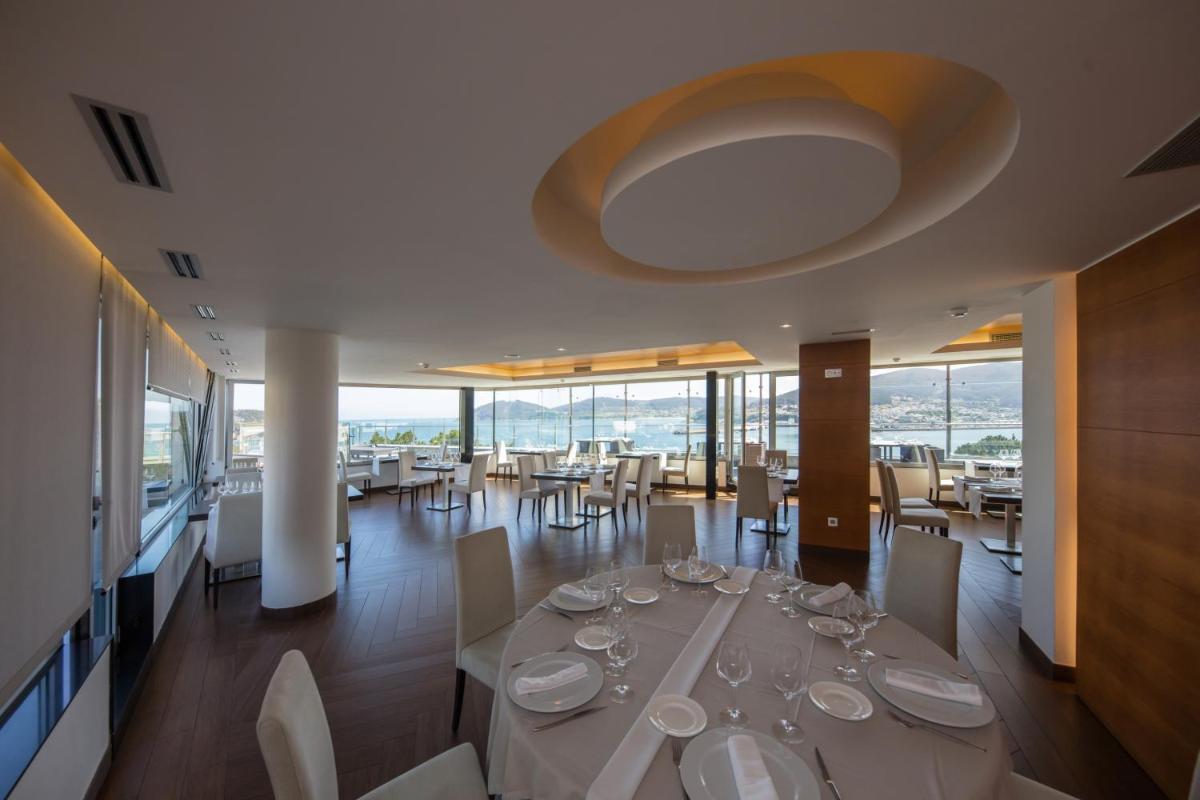 Un comedor con una mesa con copas de vino encima. en Hotel Thalasso Cantabrico Las Sirenas 4 Superior, en Viveiro