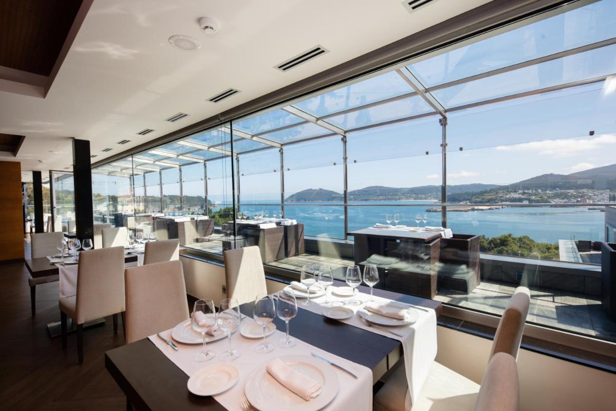 un restaurante con vistas al agua en Hotel Thalasso Cantabrico Las Sirenas 4 Superior, en Viveiro