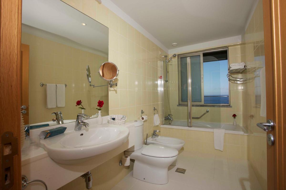 um banheiro com uma pia, um vaso sanitário e uma janela em Madeira Regency Cliff - Adults Only no Funchal