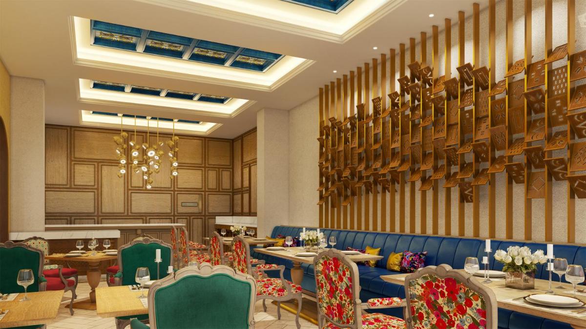 a restaurant with tables and chairs and a chandelier at Pilibhit House, Haridwar – IHCL SeleQtions in Haridwār