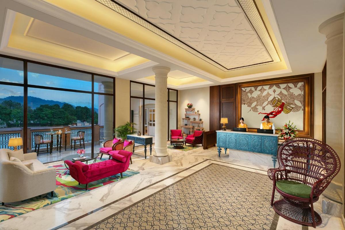 a living room with red furniture and a large window at Pilibhit House, Haridwar – IHCL SeleQtions in Haridwār