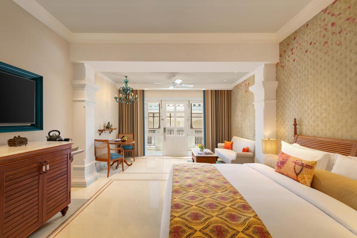a hotel room with a large bed and a living room at Pilibhit House, Haridwar – IHCL SeleQtions in Haridwār