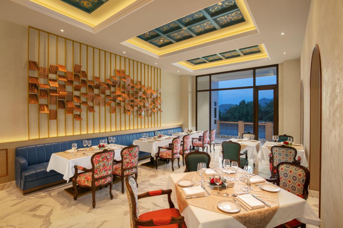 a restaurant with tables and chairs and a large window at Pilibhit House, Haridwar – IHCL SeleQtions in Haridwār