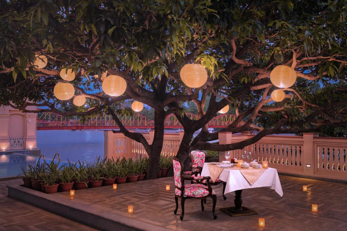a table and chairs under a tree with lights at Pilibhit House, Haridwar – IHCL SeleQtions in Haridwār