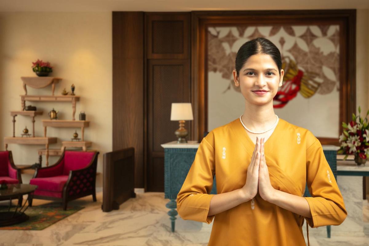 a woman is standing in a room with her hands in meditation at Pilibhit House, Haridwar – IHCL SeleQtions in Haridwār