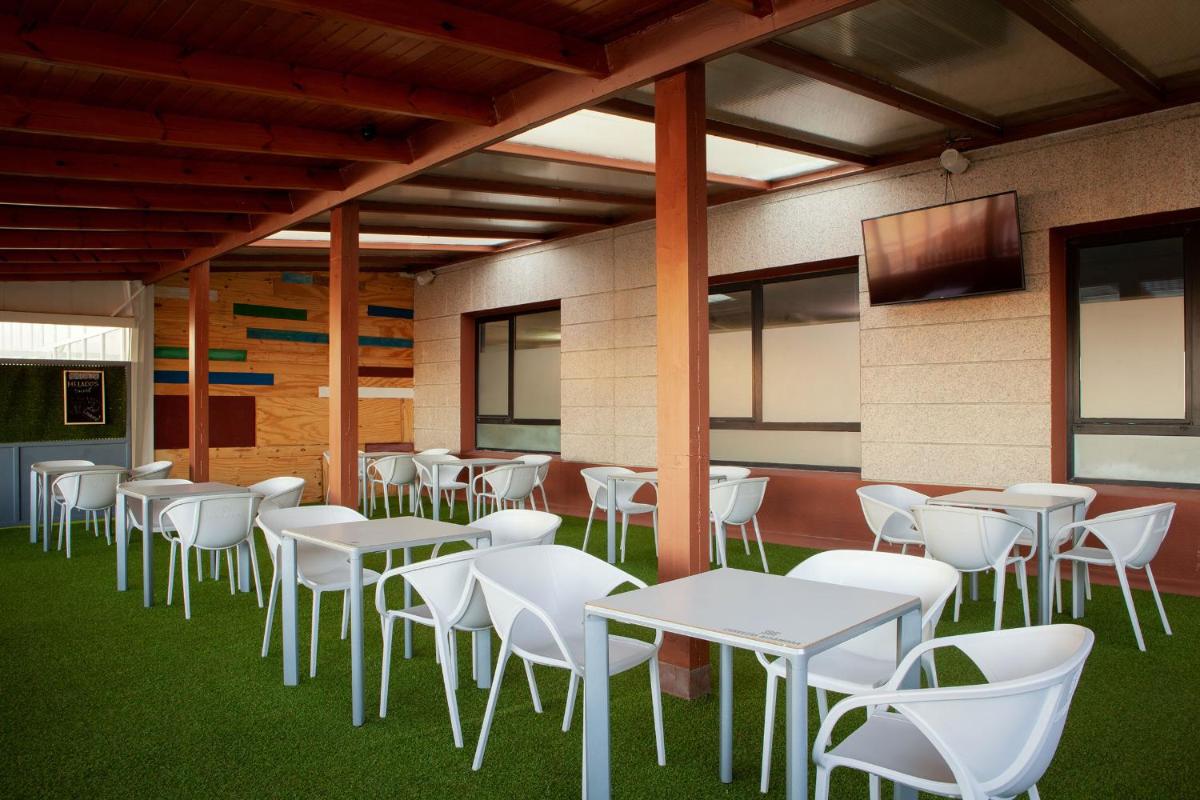 una cafetería con mesas blancas y sillas blancas en Hotel Doña Brígida – Salamanca Forum, en Villamayor