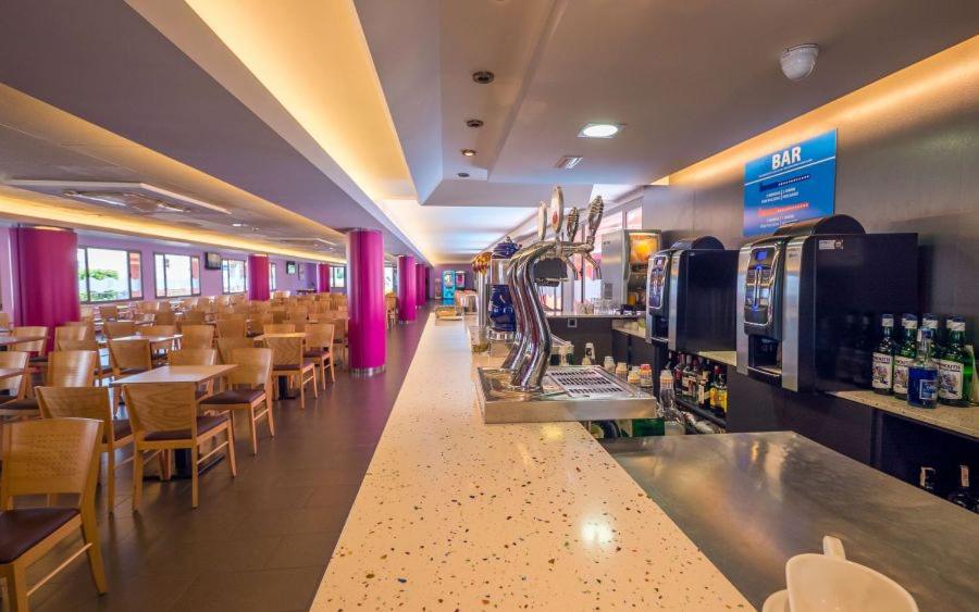 Un restaurante con barra, mesas y sillas. en Tossa Beach Center, en Tossa de Mar