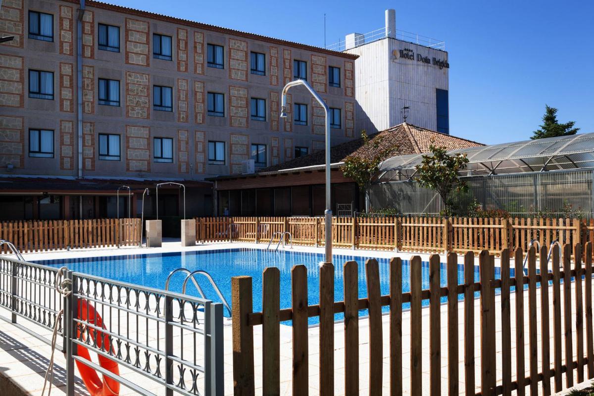 una valla alrededor de una piscina frente a un edificio en Hotel Doña Brígida – Salamanca Forum, en Villamayor