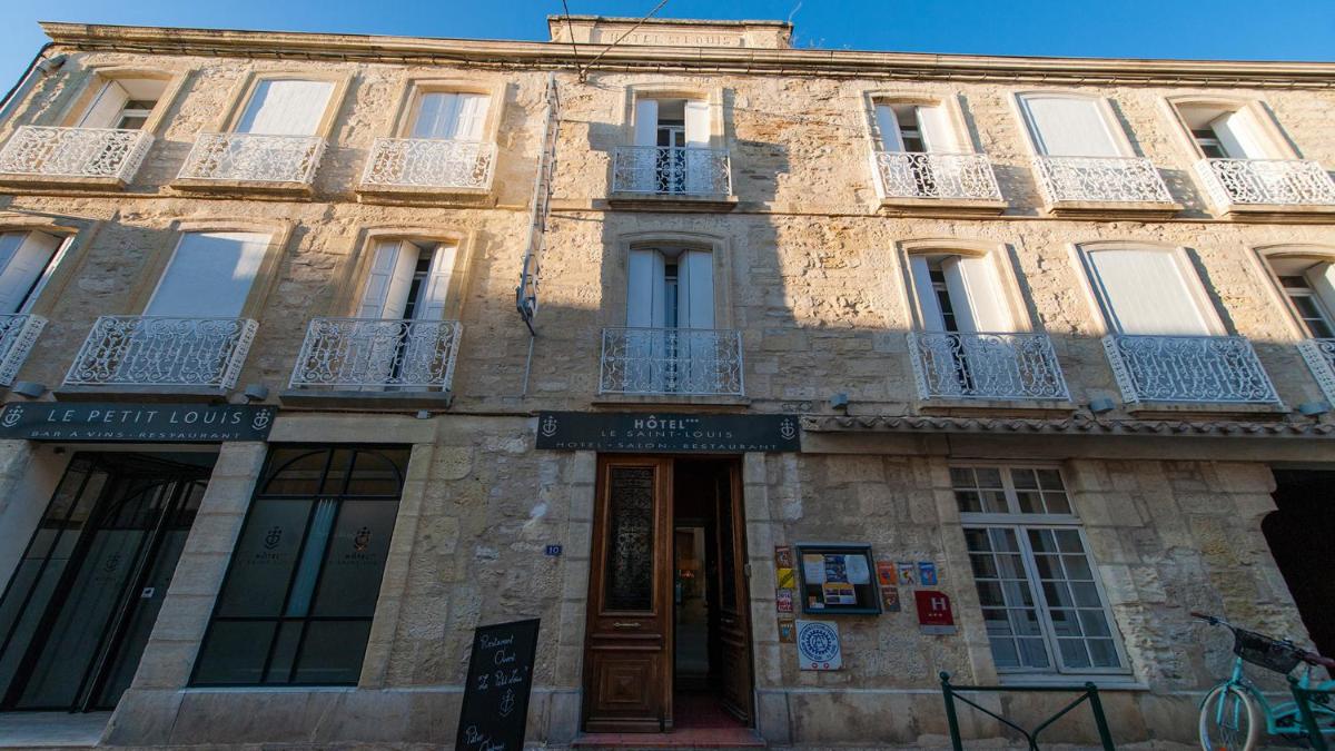 - un vieux bâtiment en pierre avec balcon dans une rue dans l'établissement Hôtel Saint Louis, à Aigues-Mortes