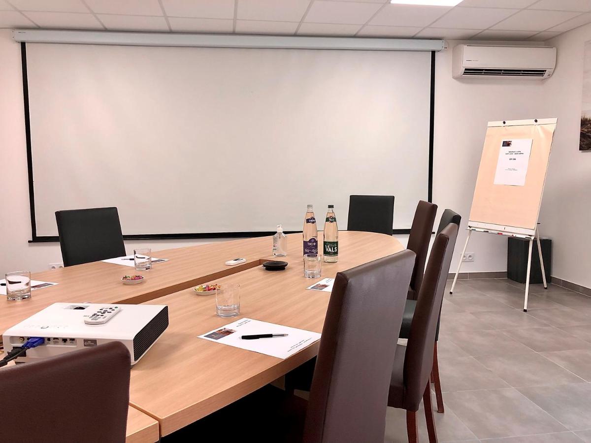une salle de conférence avec une table, des chaises et un tableau blanc dans l'établissement Hôtel Saint Louis, à Aigues-Mortes