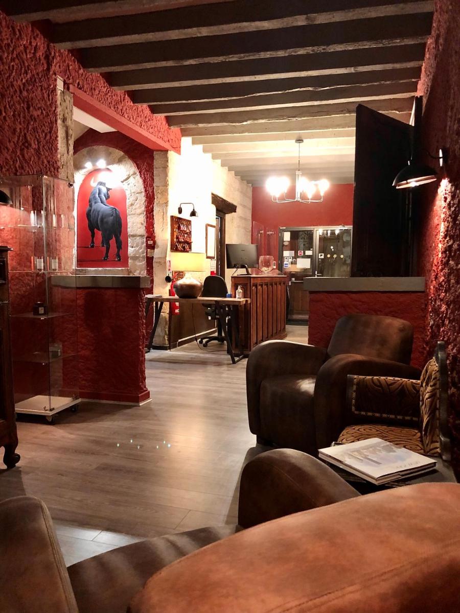 un salon avec des canapés et une pièce ornée d'une peinture d'éléphant dans l'établissement Hôtel Saint Louis, à Aigues-Mortes