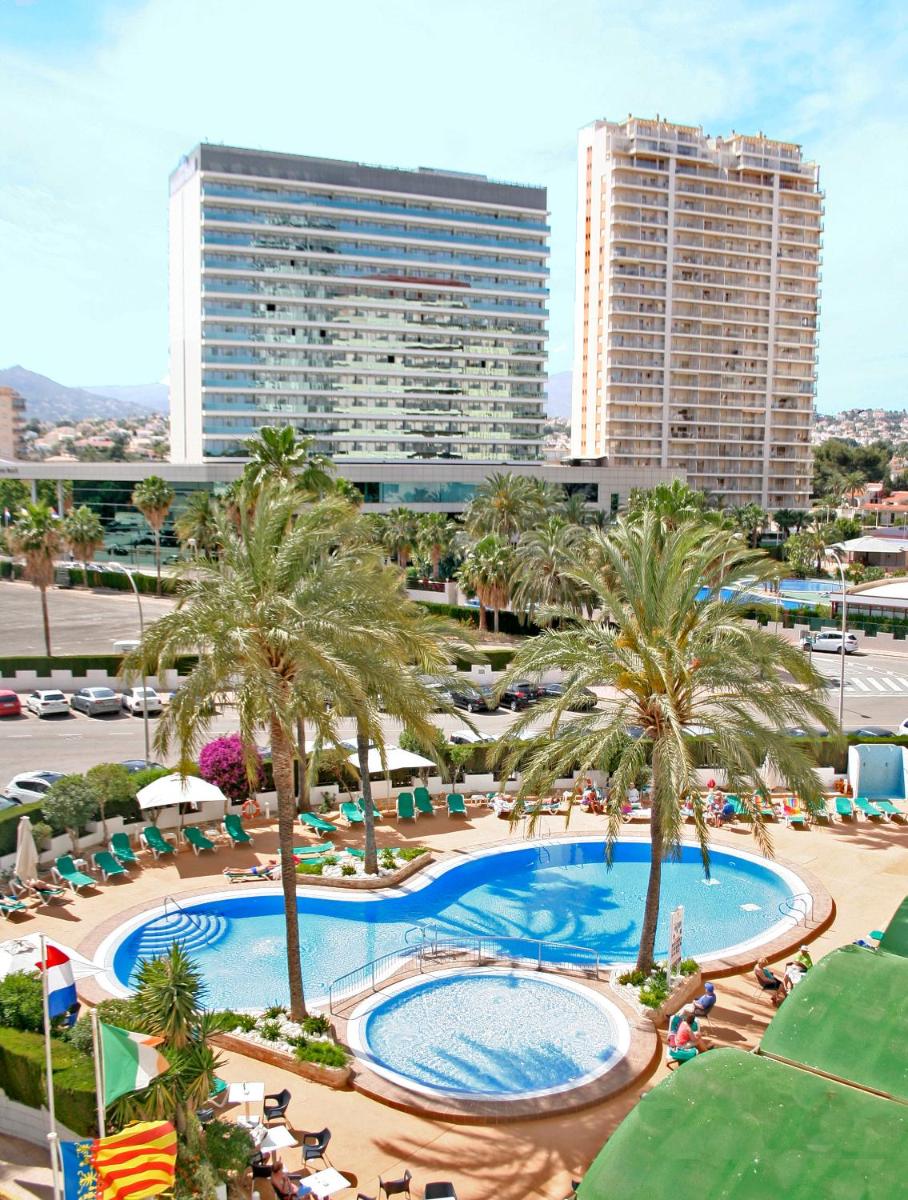 Una vista aérea de una piscina con palmeras y edificios. en AR Roca Esmeralda & SPA Hotel, en Calpe