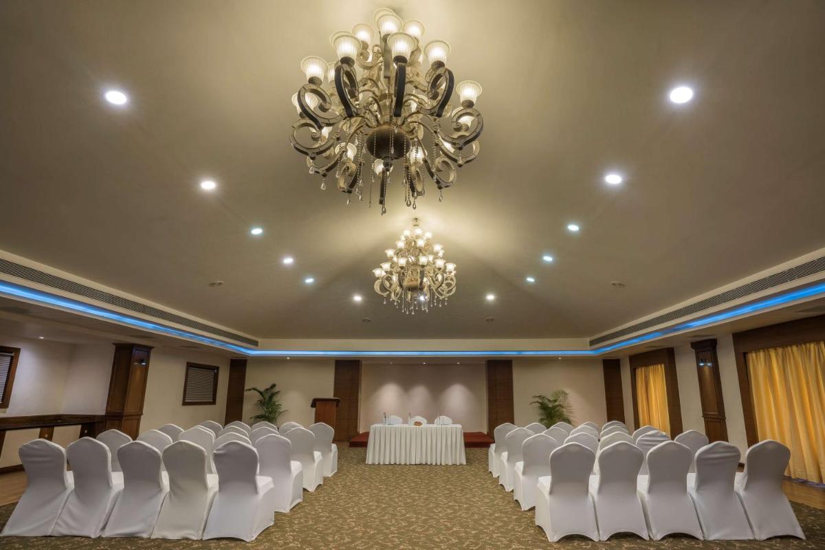 a banquet hall with white chairs and a chandelier at Radisson Goa Candolim in Candolim